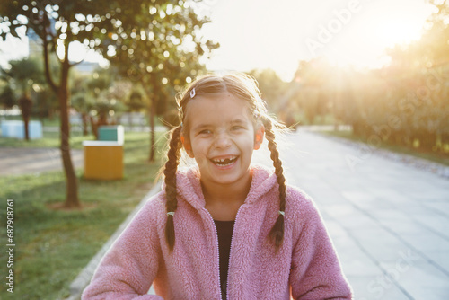 portrait of a laughing funny cheerful girl 6 years old in the park at sunset, missing front tooth.