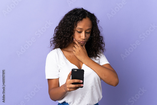 Teenager cuban girl isolated on purple background thinking and sending a message