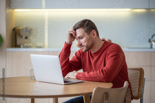 Disappointed hopeless unemployed middle aged man jobseeker sitting at table, reading advertisements on web sites, looking through vacancies, hunting for job. Depressed man after dismissal, job cut