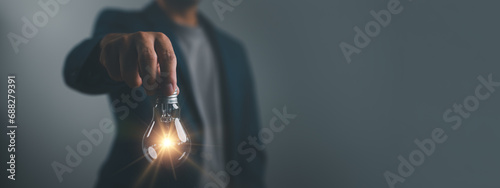 Idea concept creative thinking, Hand of man holding illuminated light bulb, idea, innovation and inspiration concept. Concept of creativity with bulbs that shine glitter.