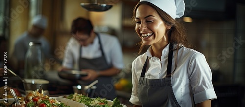 Smiling chef or waitress in apron and toque standing in restaurant