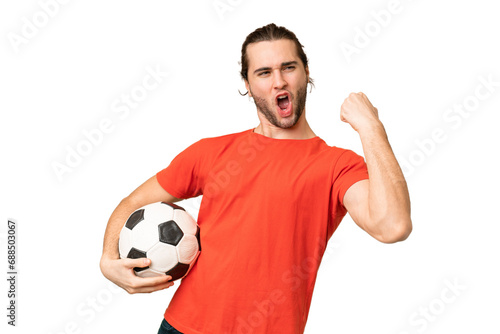 Young handsome man isolated on green chroma background with soccer ball celebrating a victory