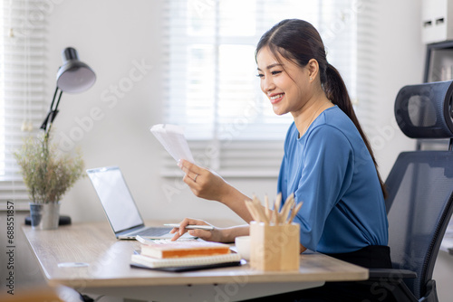 asian woman using calculator and calculate bills in home office. tax form us business income office Financial document. Tax time.Tax concept.