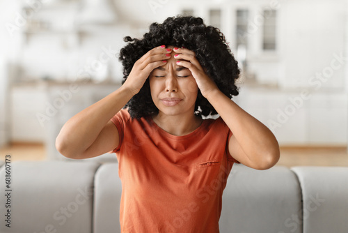 Headache Concept. Young black woman suffering from migraine at home