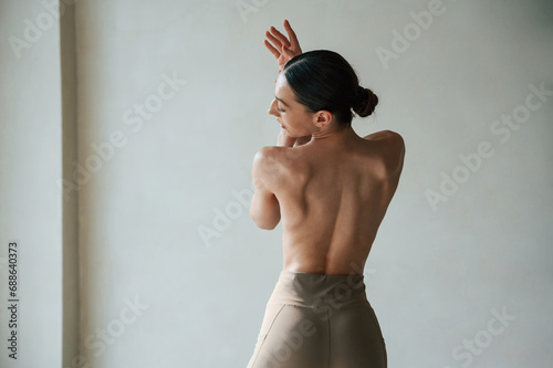 Back view of sporty woman that is without bra indoors