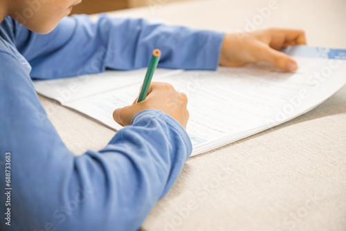 Caucasian elementary school child doing homework at the end of the school day. Close up and copy space.
