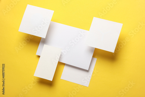 Composition of floating white square memo paper and cards on yellow background. Mockup. Business concept