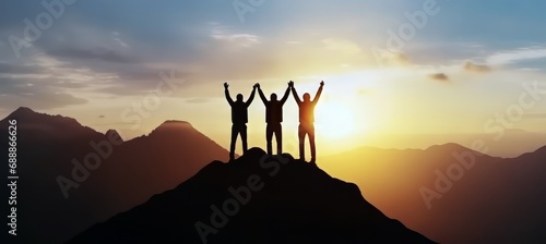 Celebrate victory and success over sunset background, Together overcoming obstacles as a group of three people raising hands up on the top of a mountain.
