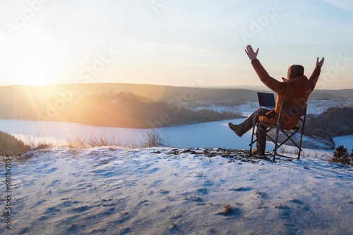 happy man with laptop working outdoor in winter. businessman sitting using computer and enjoying winter. freedom, remote work concept.
