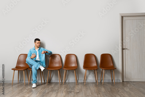 Young man with mobile phone waiting for his turn in room