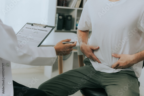 Crohn's disease or ulcerative colitis concept. Doctor counseling male patient with abdominal pain in hospital examination room