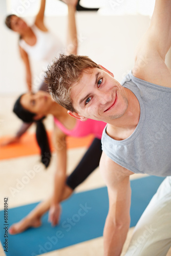 Portrait, smile and stretching, happy man in yoga class for fitness, commitment and body wellness. Pilates, men and women in gym together for holistic health, mindfulness and person at exercise club.