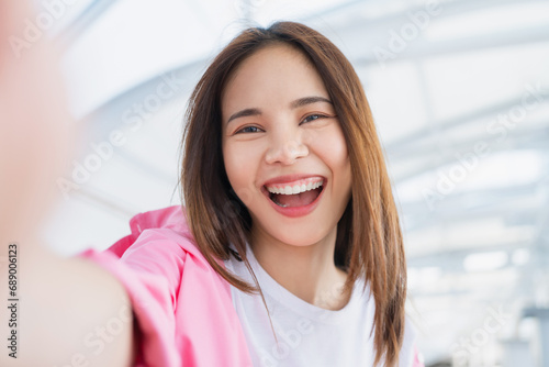 Happy young Asian woman smiles and taking selfie photo in the airport to travel.