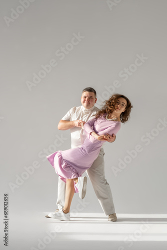 Beautiful young couple dancing on light background. Full length of young beautiful couple bonding while standing against white background