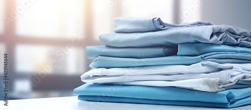 Industrial laundry providing a cleaning and ironing service for hotels clinics and companies with stacks of clean folded sheets and fabrics and an industrial iron Copy space image Place for add