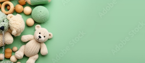 Eco friendly handmade baby toys on a mint background including wooden rattles a crocheted teddy bear and teething beads Copy space image Place for adding text or design
