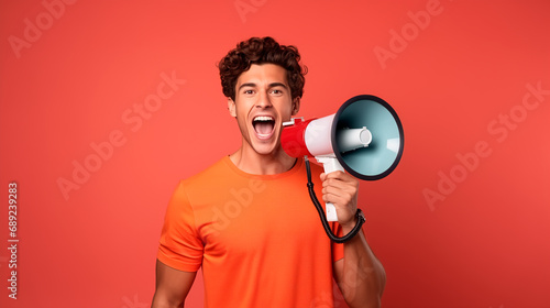 Young man on an orange background holding a megaphone making a call