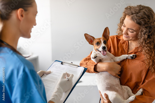 Vet with chart; woman holds happy dog