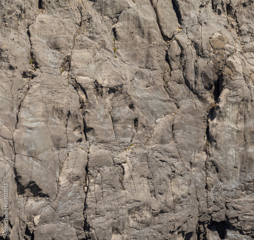 Weathered seaside rock face texture. Aged volcanic stone wall surface background pattern with cracks and scratches. Ischia Island, Italy.