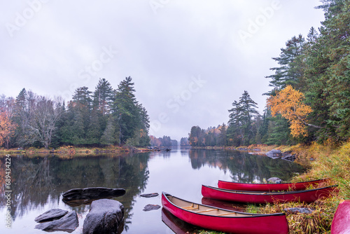 canoes on the shore of a calm reflective part of the lower madawaska river ontario in fall with autumn color room for text