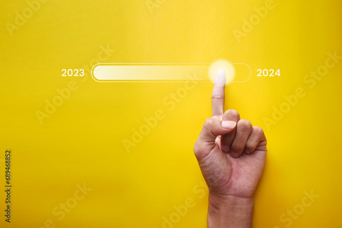 Finger touching status bar changing from 2023 to 2024 for countdown Merry Christmas and New Year with technology concept, Starting a new business and new life.