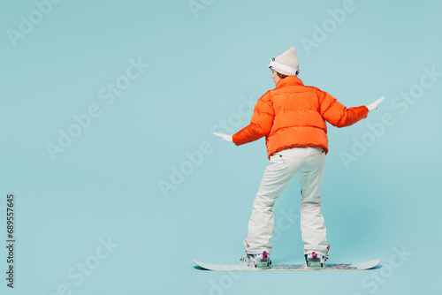 Full body back rear view young woman she wear warm padded windbreaker jacket hat ski goggles mask snowboarding travel rest spend weekend winter season in mountains isolated on plain blue background.