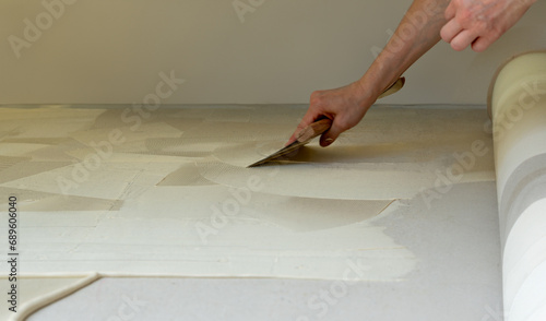 Man prepares the floor with glue for a new carpet.