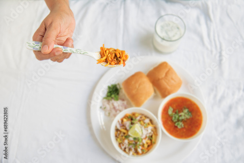 A lady holding a byte of Maharashtrian indian traditional breakfast food Misal Pav with Buttermilk