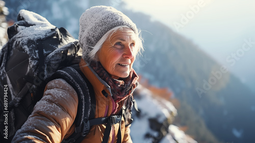 An elderly gray-haired woman climber conquers a narrow ridge high in the snow-capped Alpine mountains
