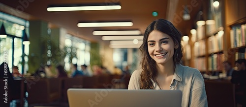 Education university and happy woman in library with laptop research and books for school project or exam Smile internet and college phd student studying with technology and elearning on campus