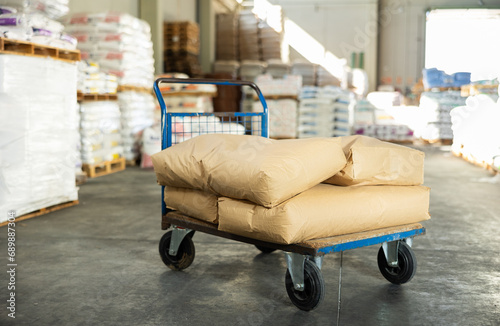 Paper bags are stacked on top of each other and lie in large stacks in warehouse of building materials store. Bundles of soil and fertilizers lie in large pile in back room of wholesale supermarket