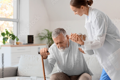 Nurse helping senior man to stand up at home