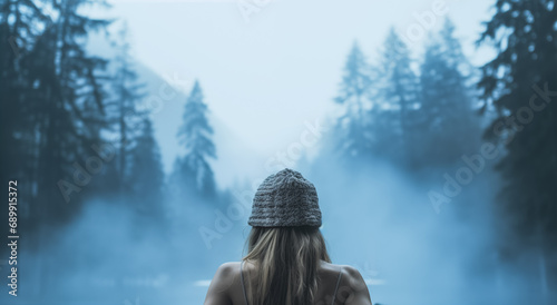 Woman relaxing in hot bath outdoors, enjoying beautiful view on snowy mountains. Winter holidays in the mountains, hot water treatments concept. 