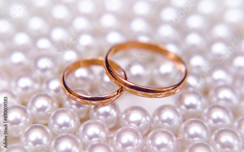 Gold wedding rings lie on a pearl necklace 