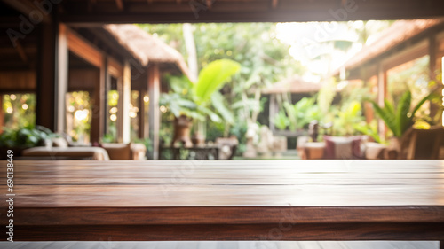 An empty wooden table foregrounds a blurred Balinese-style interior, inviting a serene and tropical atmosphere perfect for a calm setting.