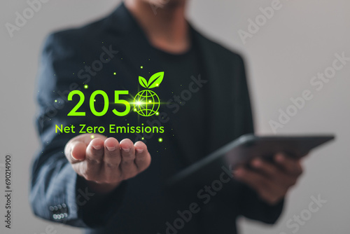 Net zero emissions by 2050. Businessman holding virtual Net Zero icon to change climate and net zero greenhouse gas emissions target. Sustainable development and green business concept.