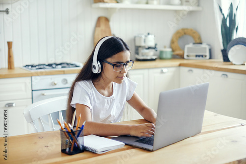 Girl in headphones and eyeglasses e-learning at home