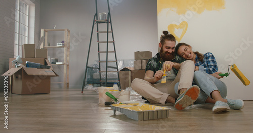 Newlywed caucasian couple is renovating their new home, painting the walls and positively smiling - new life, young family, mortgage concept 