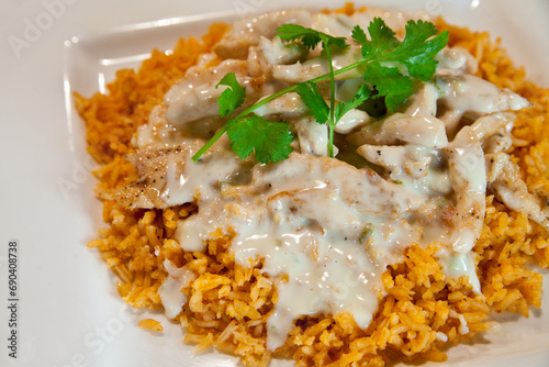 Close-up of Arroz con Pollo, Grilled Chicken on Seasoned Rice with Creamy Sauce and Cilantro Garnish