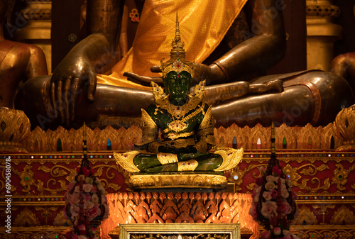 An emerald Buddha statue with golden crown and costume decoration situated in Wat Phra Kaew temple in Chiang Rai province of Thailand.