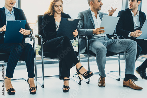 Businesswomen and businessmen holding resume CV folder while waiting on chairs in office for job interview. Corporate business and human resources concept. uds