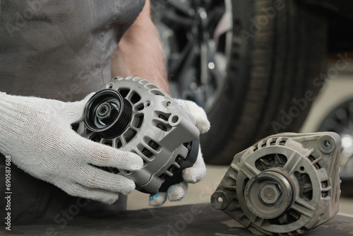 A generator for an automobile engine on the car mechanic's desktop. A specialist examines the new generator. Monitoring the integrity and compliance of a new product when replacing a faulty generator.