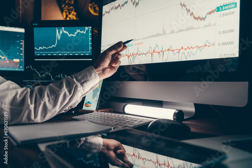 Close-up of male trader pointing computer monitor while analyzing stock market charts in office