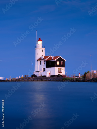A lighthouse on the beach during blue hour. A landmark in maritime navigation. Long exposure. Natural composition. Photo for wallpaper and background. Paard van Marken, Netherlands.