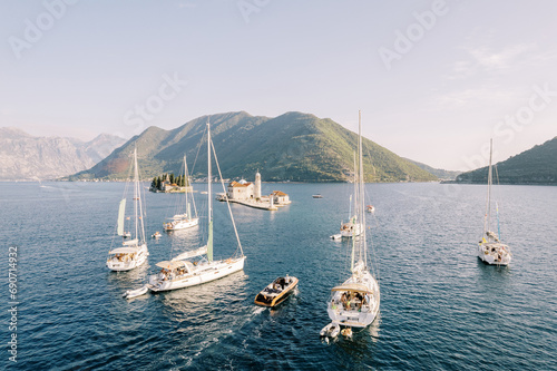 Motor yacht and sailboats sail along the Bay of Kotor to the island of Gospa od Skrpjela. Montenegro. Drone