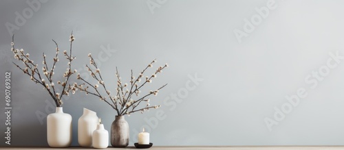 Tree branches with introduced buds in a glass vase and candles on a wooden coffee table Scandinavian living room decor. Copyspace image. Header for website template