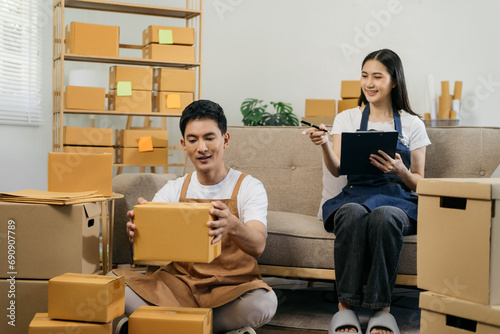 Young couple checklist with cardboard box at home - Business online and delivery concept.