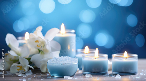 Natural soy burning candles surrounded by fresh flowers. Spa relaxation, aromatherapy, spa center wallpaper in blue white colors.