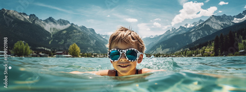 child in sunglasses in the pool against the background of the mountains