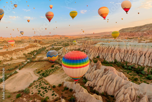 Cappadocia balloons in the sky. They capture first solar rays, casting an enchanting glow on the distinctive formations beneath them in Goreme Rose Valley, situated in Turkey's region of Cappadocia.